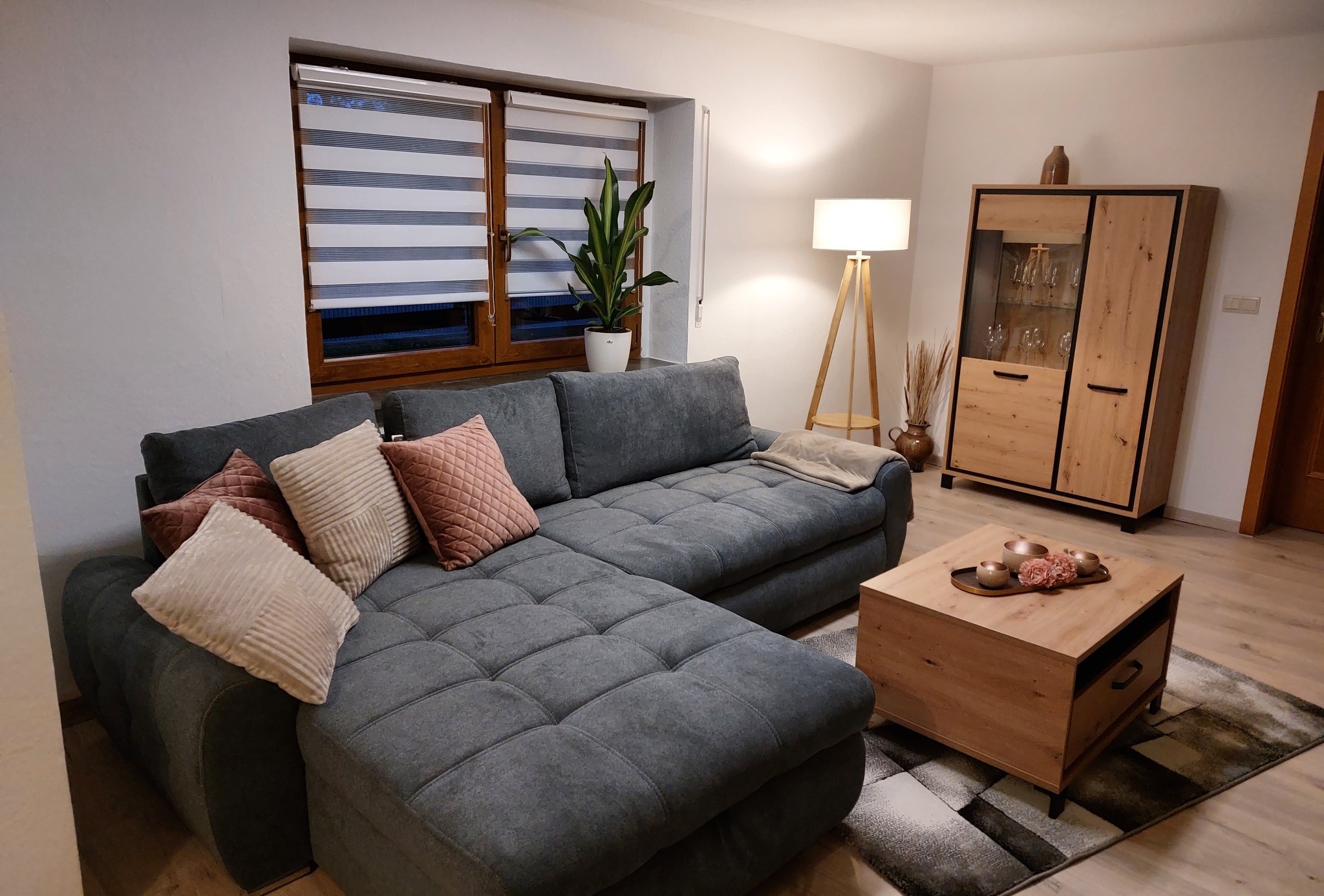 Blick in das Wohnzimmer der Ferienwohnung mit Couch, Tisch und Schrank.