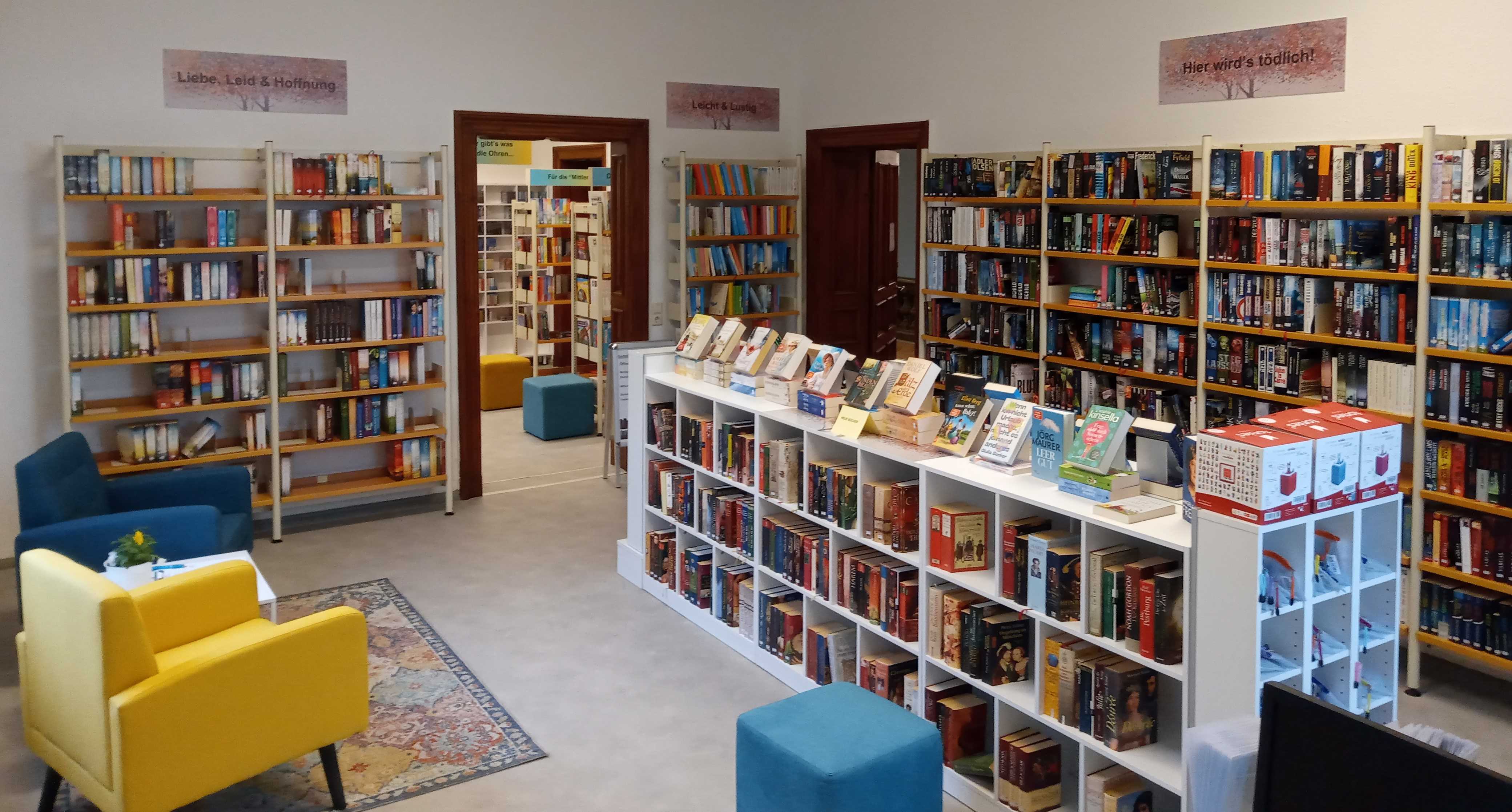 Blick in die Gemeindebibliothek mit Bücherregalen und Sitzecke.